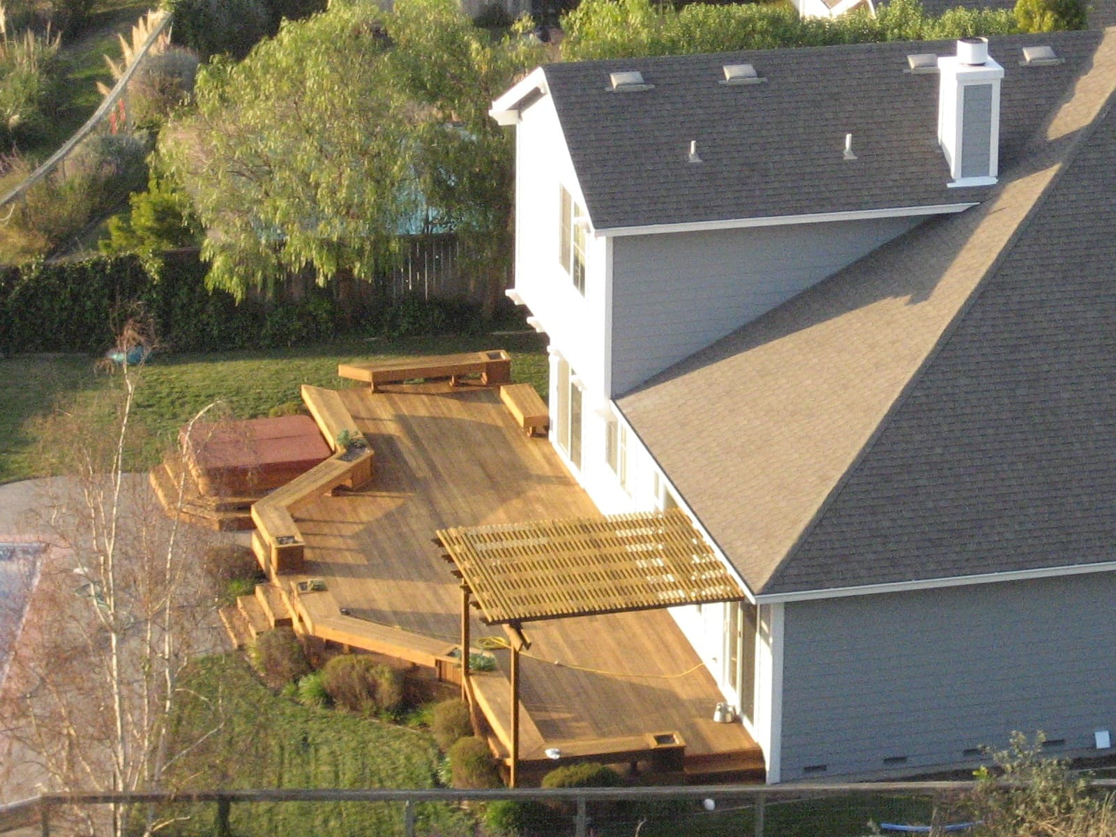 A timber backyard deck with stairs descending into a planted garden.