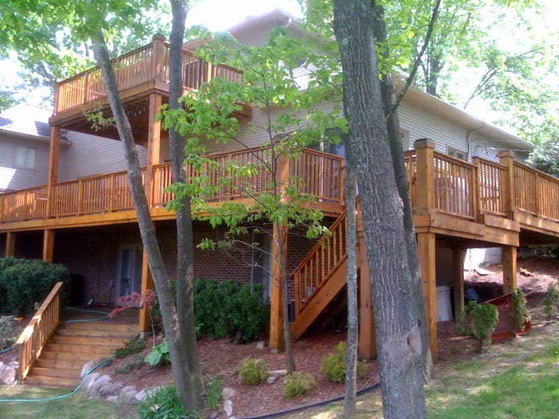 Partly stained cedar decking boards, the wet colour of fresh oil against weathered timber.