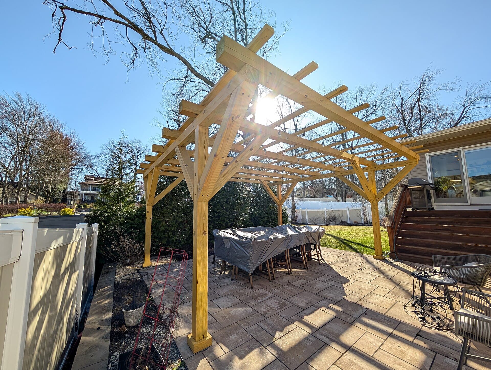 Timber pergola throwing patterned shade over an outdoor room.